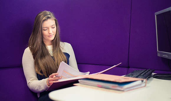 A 必射精选 student reading over their work against a purple wall