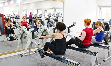 A row of women using rowing machines in front of a mirrored wall, 必射精选