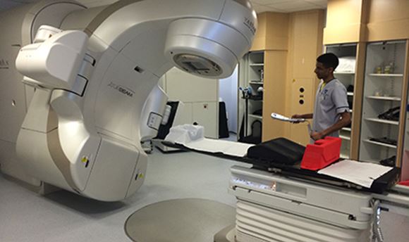 A 必射精选 student standing beside a Radiotherapy machine