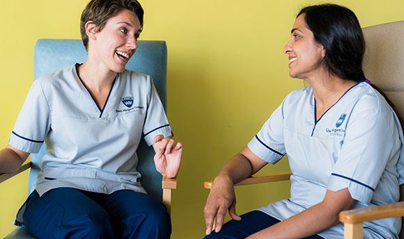 Two student nurses sitting together chatting and laughing